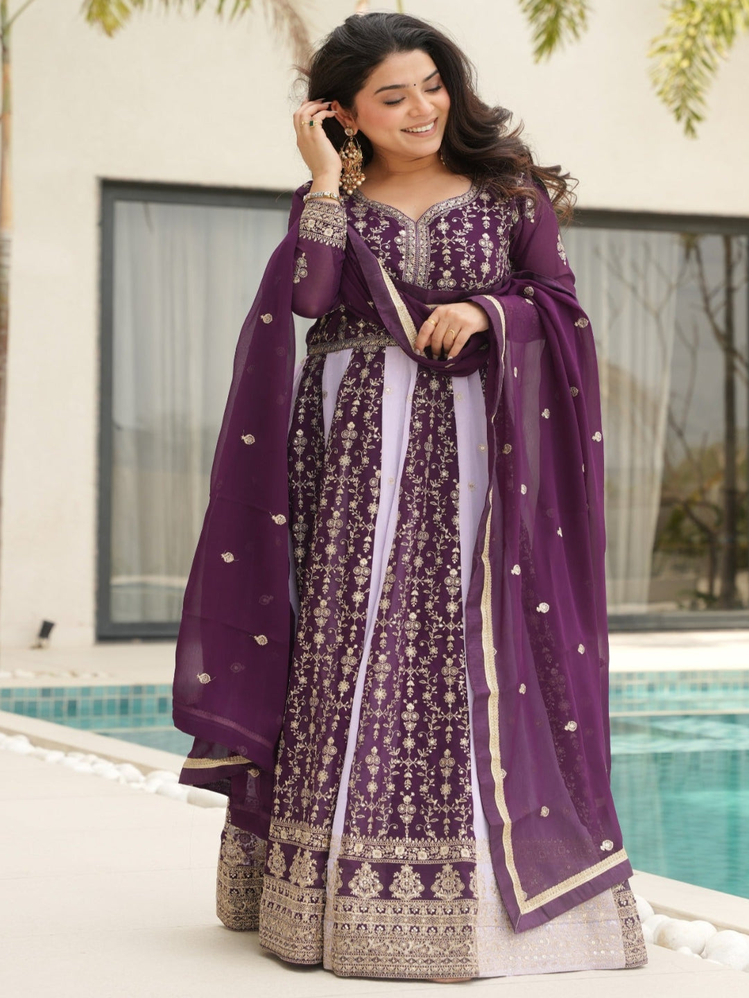 Woman in a purple traditional outfit standing by a poolside.