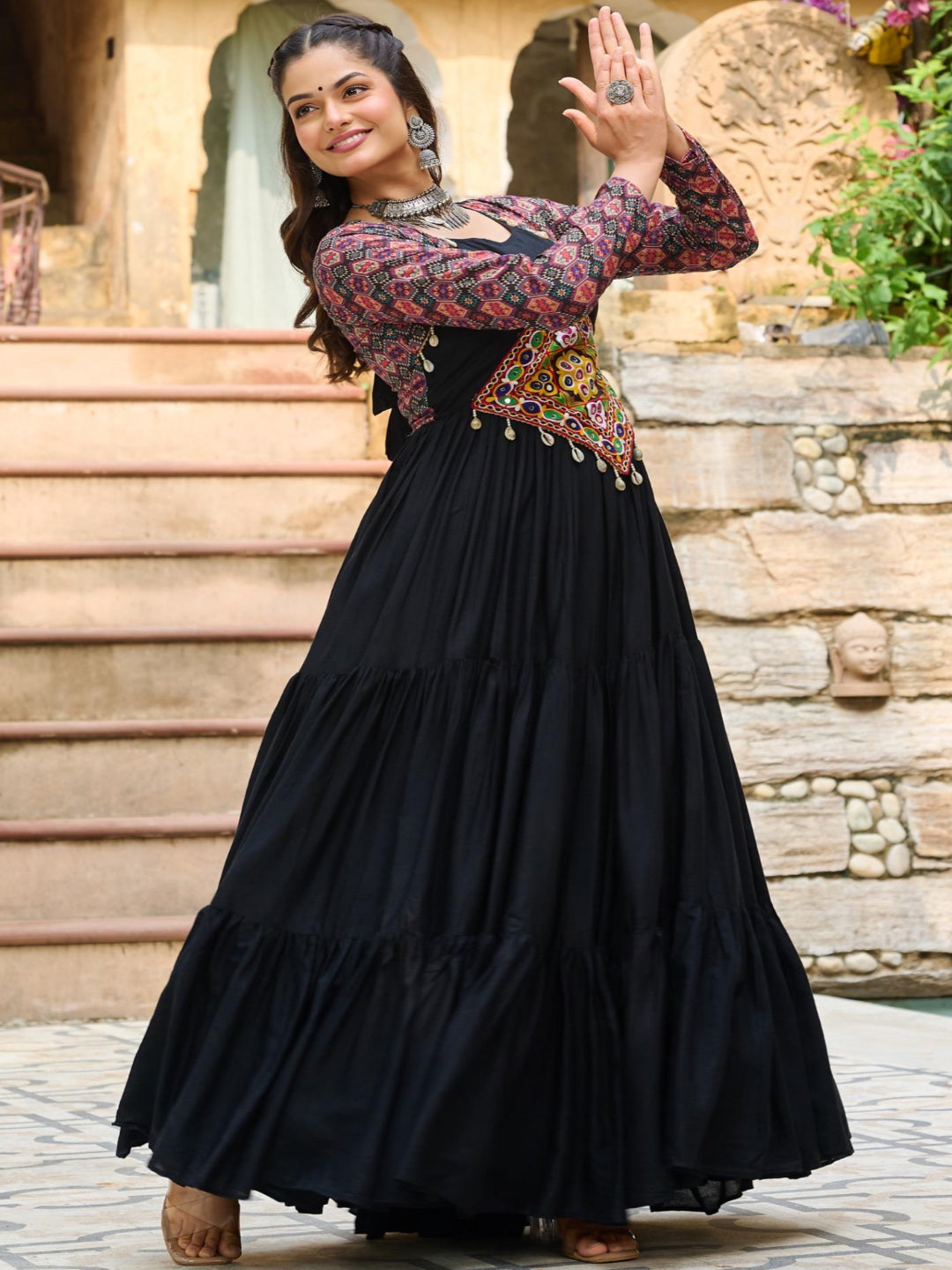 Woman in a black traditional outfit with floral patterns standing outdoors.