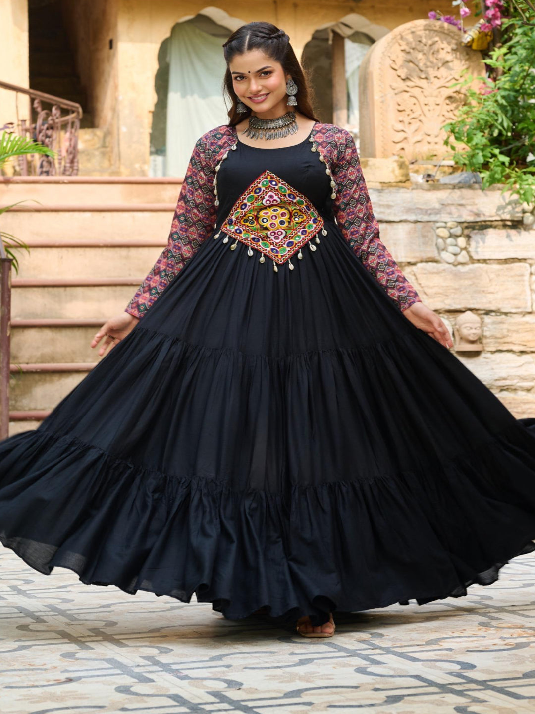 Woman in a black traditional outfit with floral patterns standing outdoors.