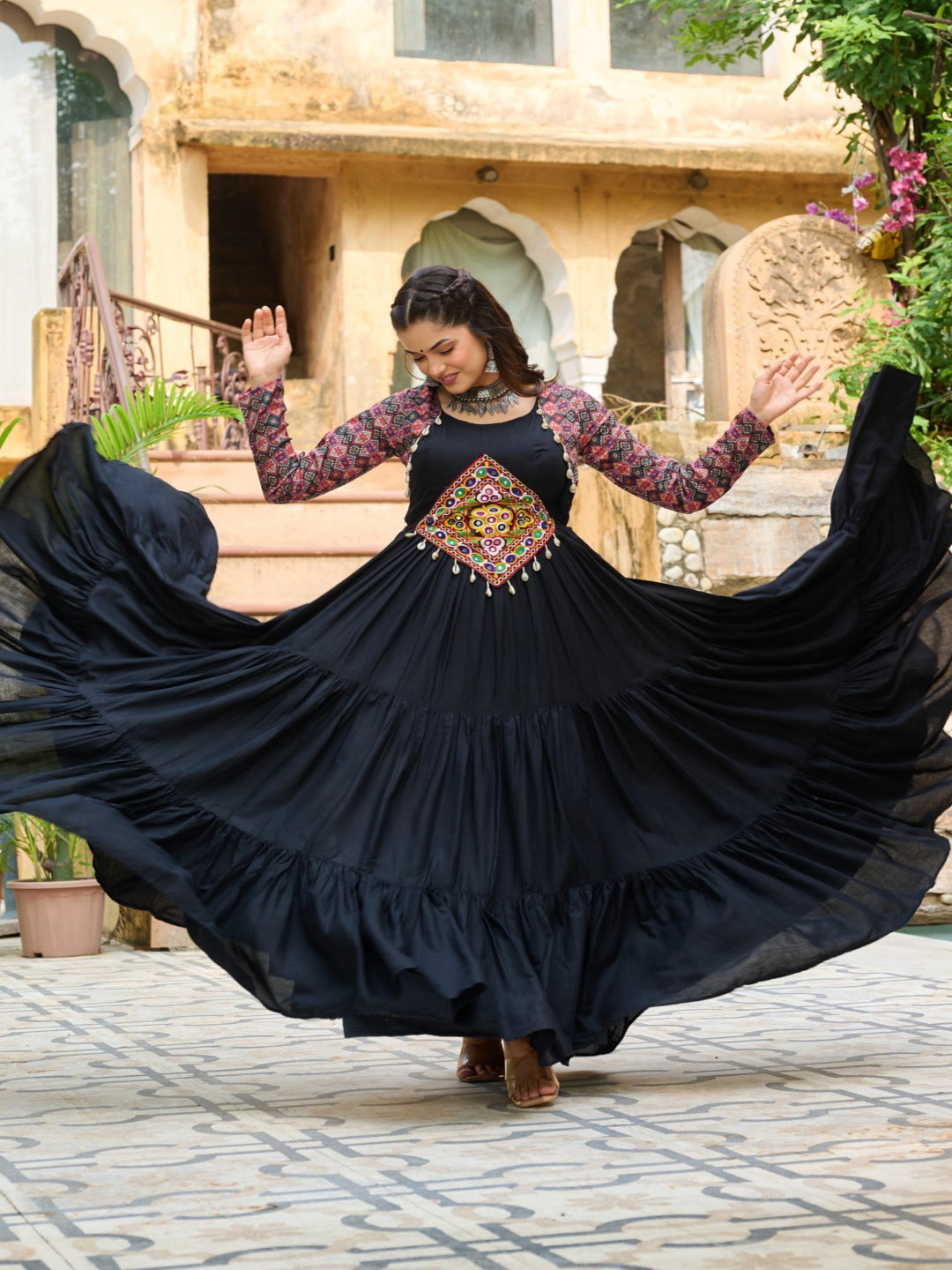 Woman in a black dress with floral patterns dancing outdoors.