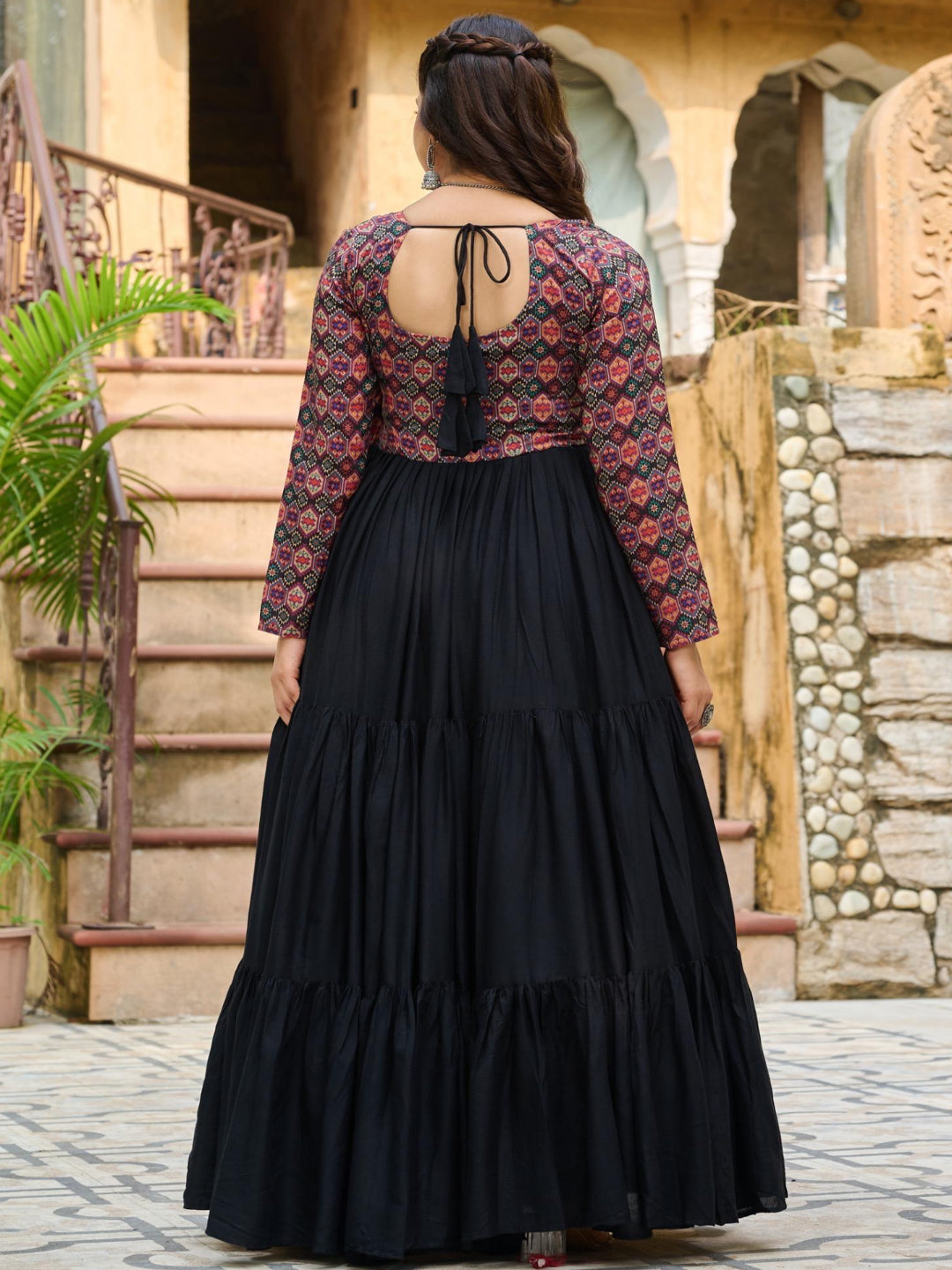 Person wearing a black dress with a patterned top in an outdoor setting.