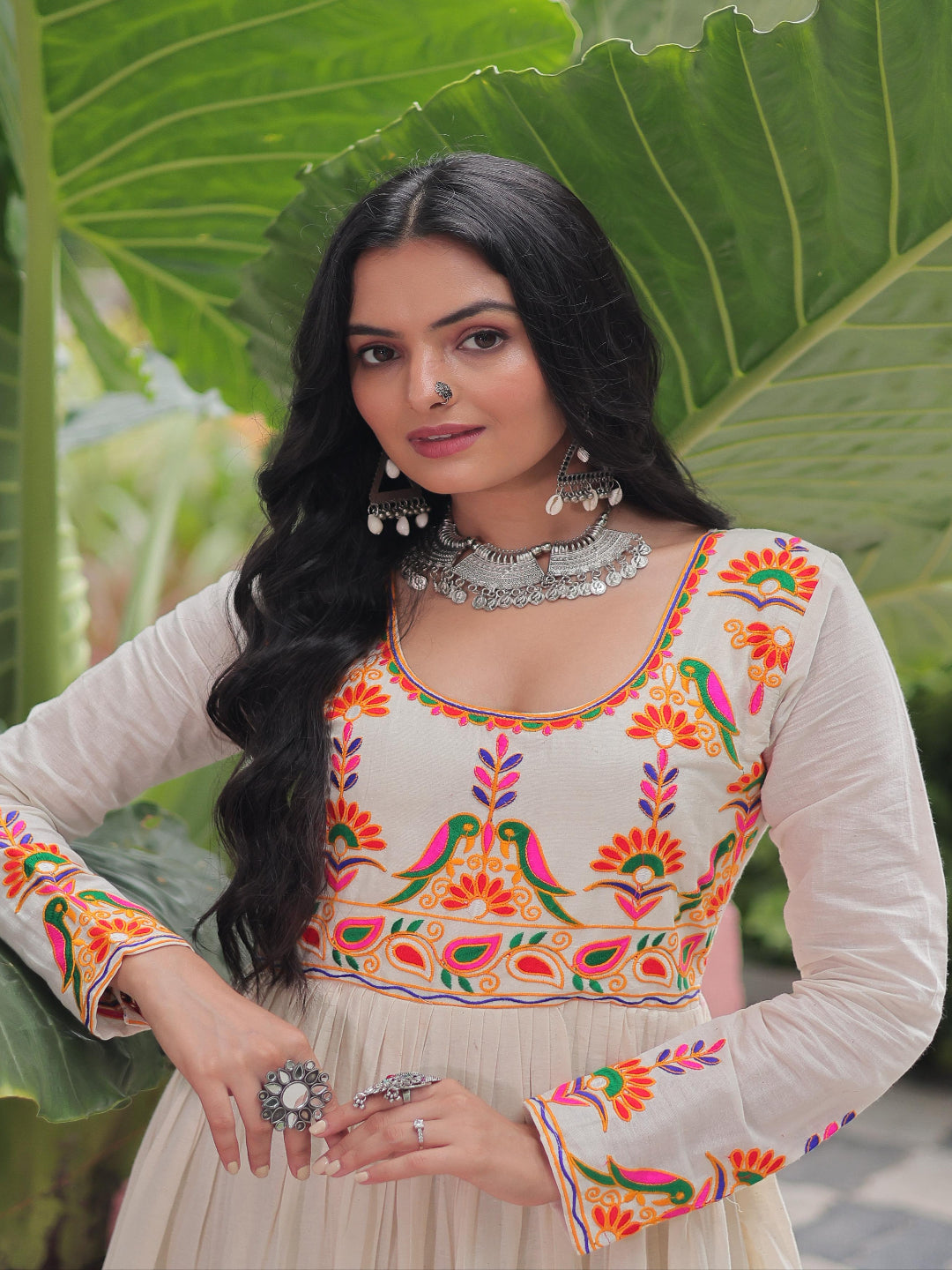 Woman wearing a colorful embroidered traditional outfit with a green leafy background