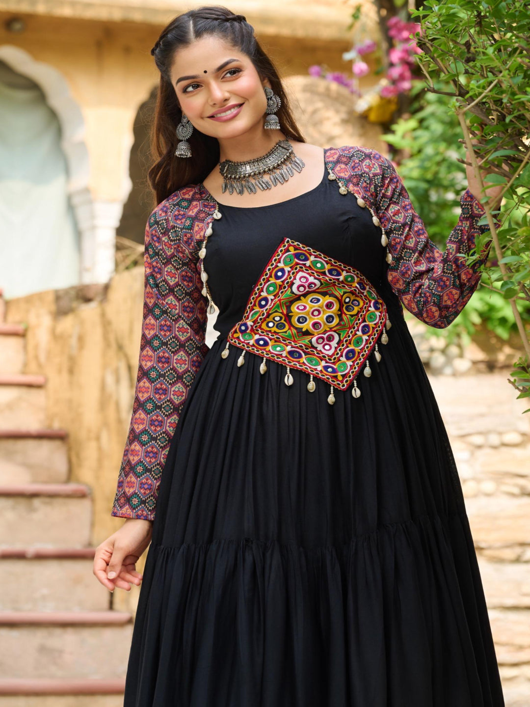 Woman wearing a black dress with colorful embroidery in an outdoor setting