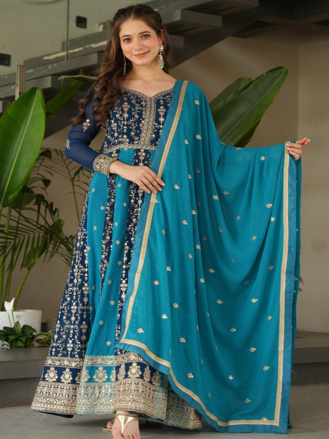 Woman in a blue and black traditional outfit with a matching dupatta in an indoor setting.