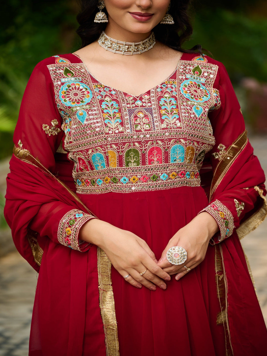 Red traditional outfit with intricate multicolored embroidery on a blurred natural background