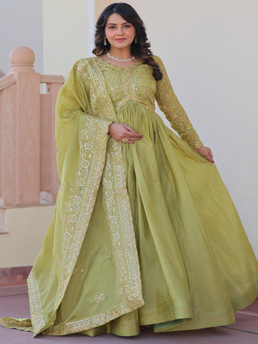 Woman wearing a green traditional outfit with embroidery indoors.