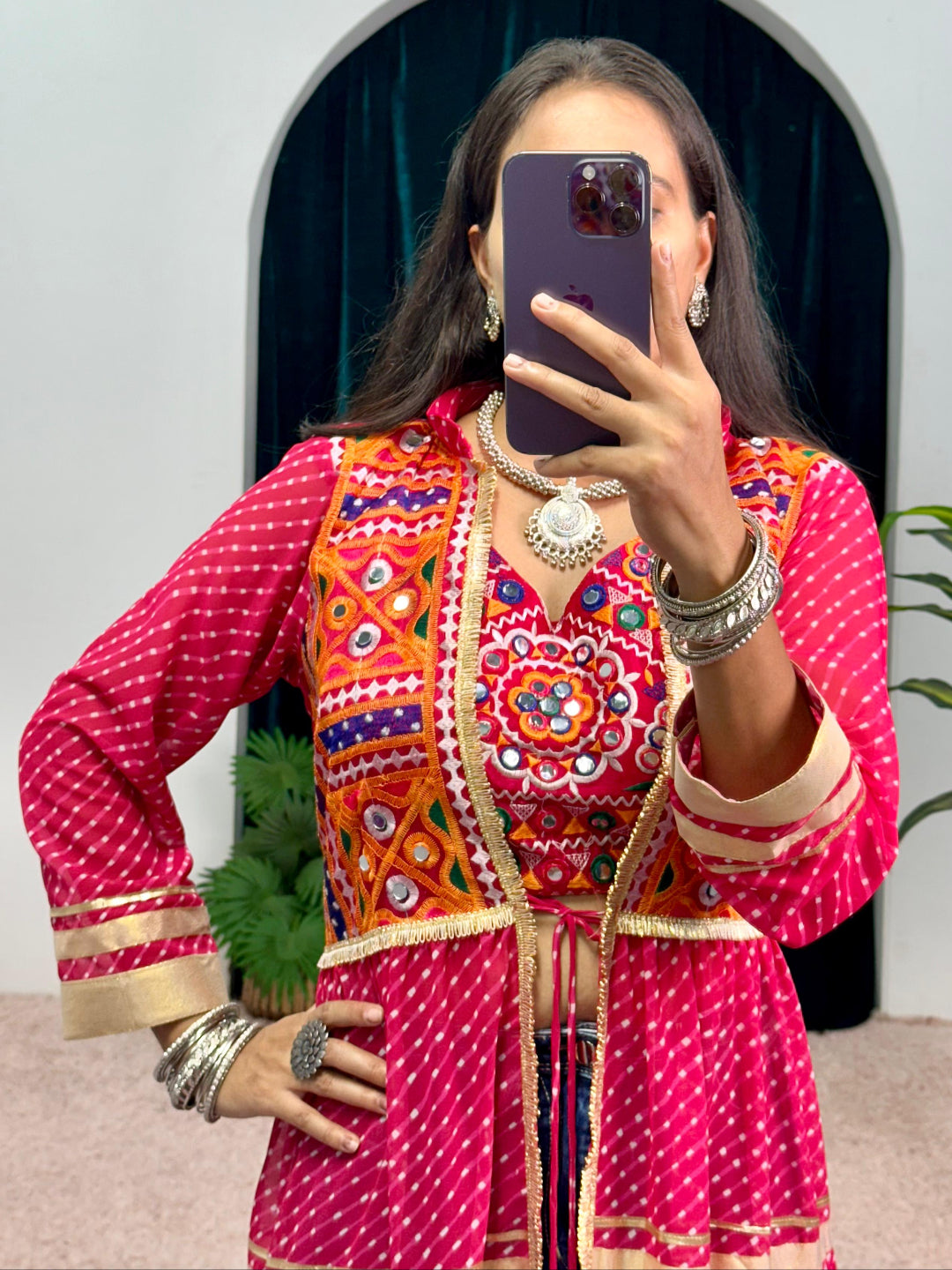 Person taking a mirror selfie wearing a traditional outfit with intricate designs.