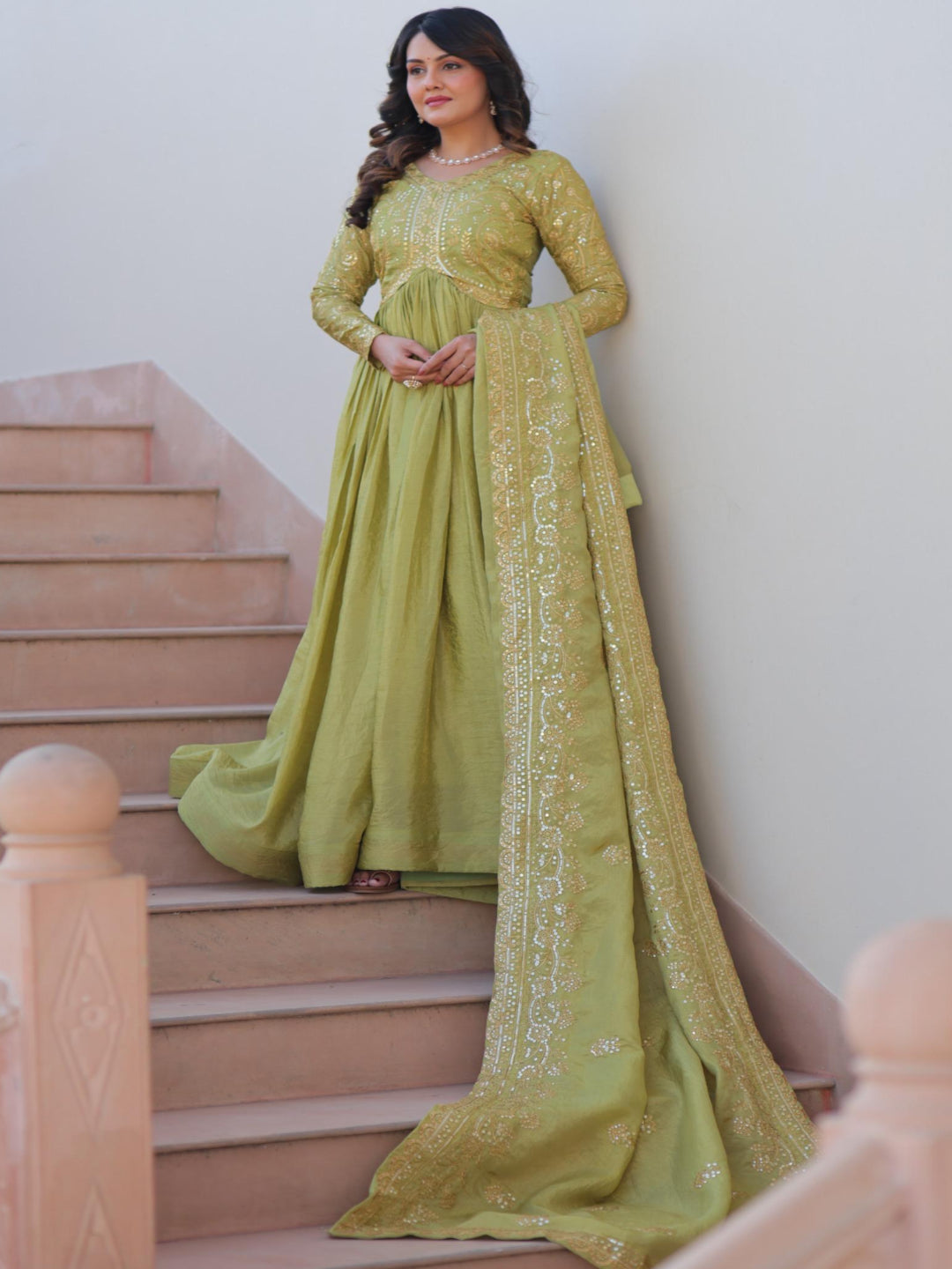 Woman in a green traditional outfit standing on a staircase