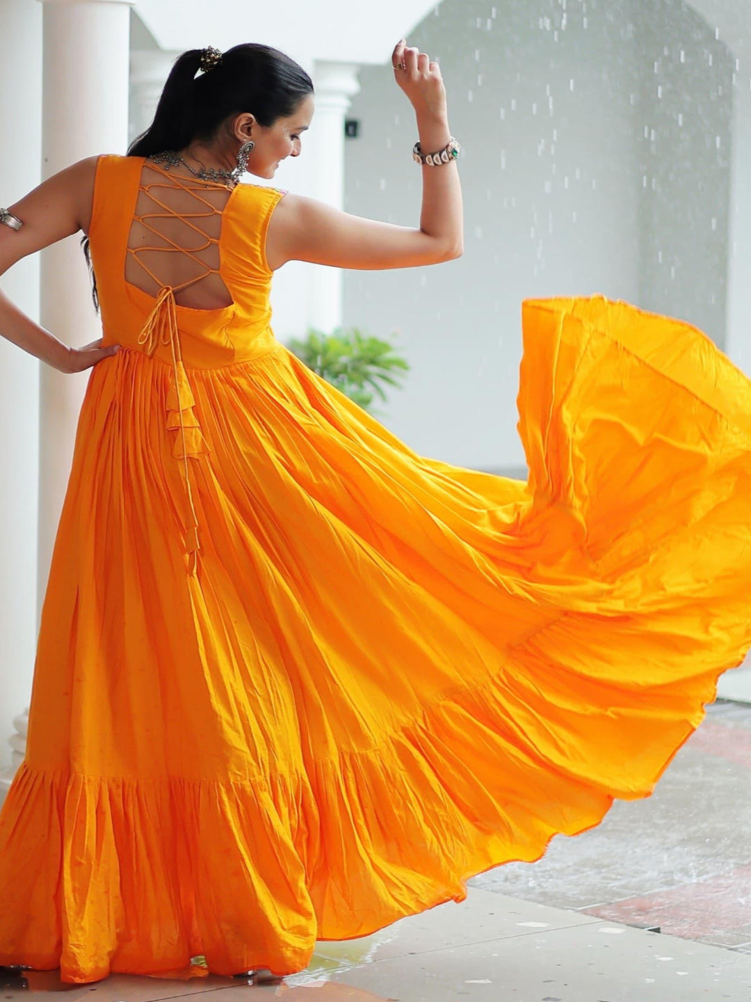 Woman in a bright yellow dress with a flowing skirt, standing in a sunlit outdoor setting.