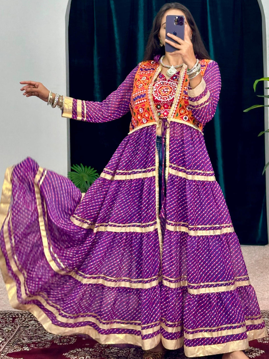 Person wearing a purple traditional outfit with gold details in front of a dark archway.