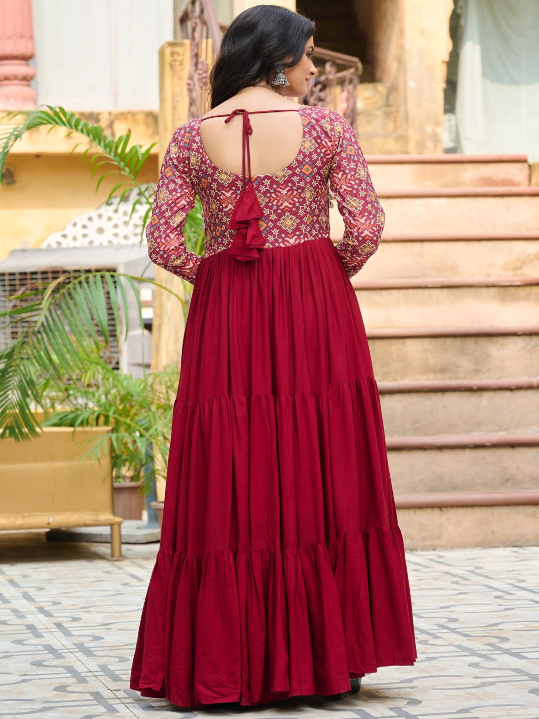 Woman wearing a red and floral dress standing outdoors.