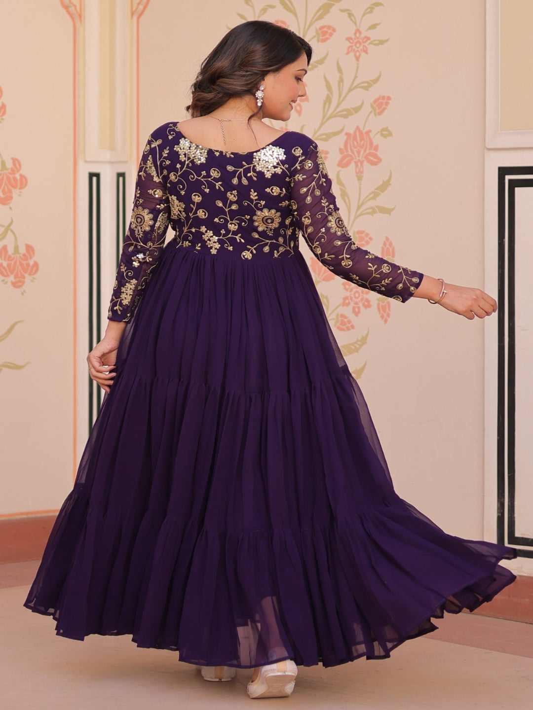 Woman in a purple dress with floral patterns in an ornate room.