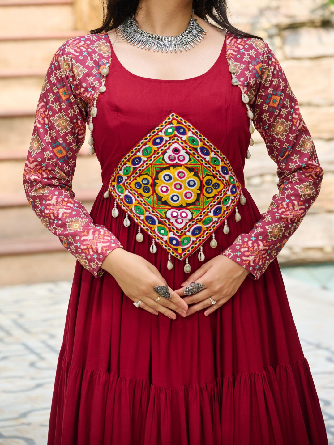 Red traditional outfit with colorful embroidery and patterned sleeves against a blurred background