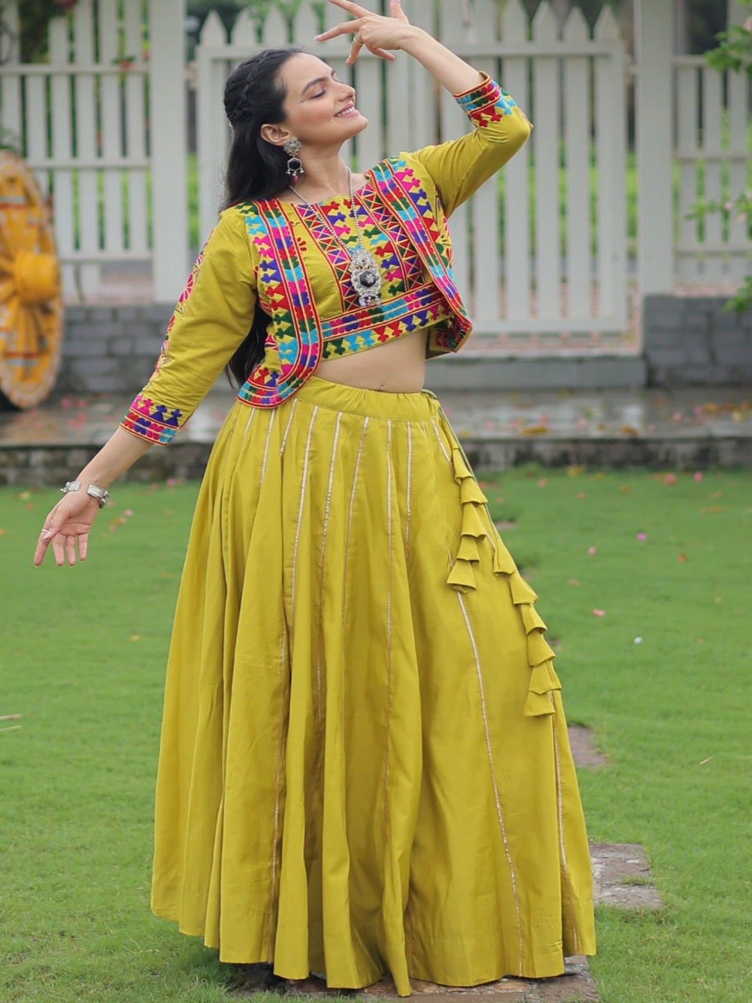 Woman in a colorful traditional outfit standing in a garden