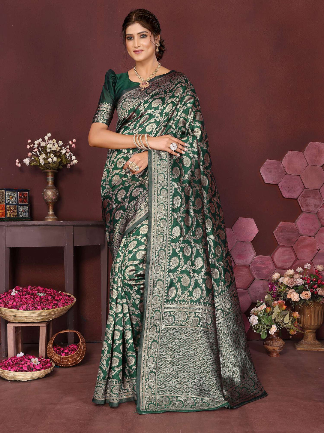 Woman wearing a green saree with a floral pattern in a decorated room.
