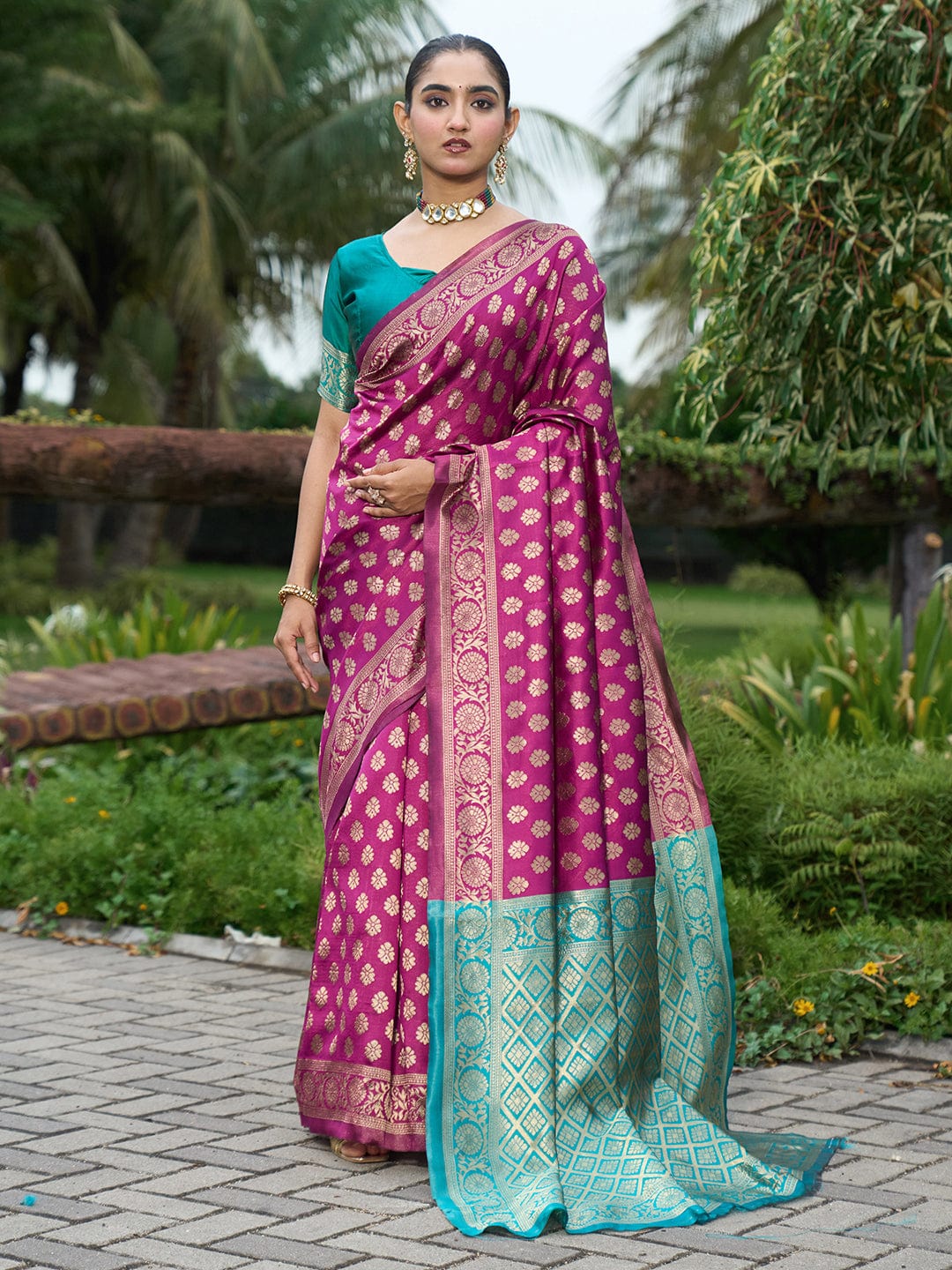 Woman wearing a pink and green saree with a garden background