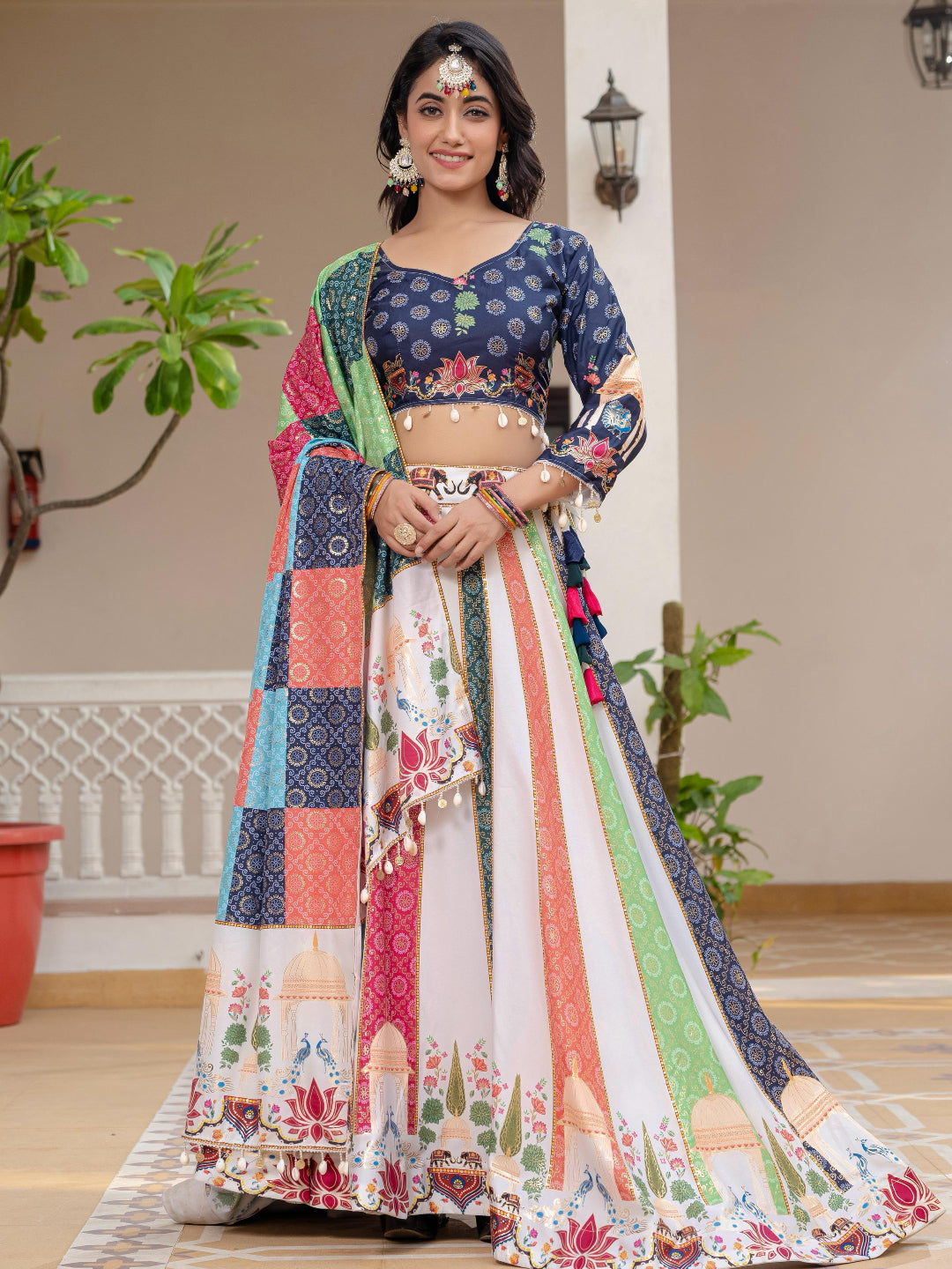 Woman in a colorful traditional outfit standing indoors with plants in the background