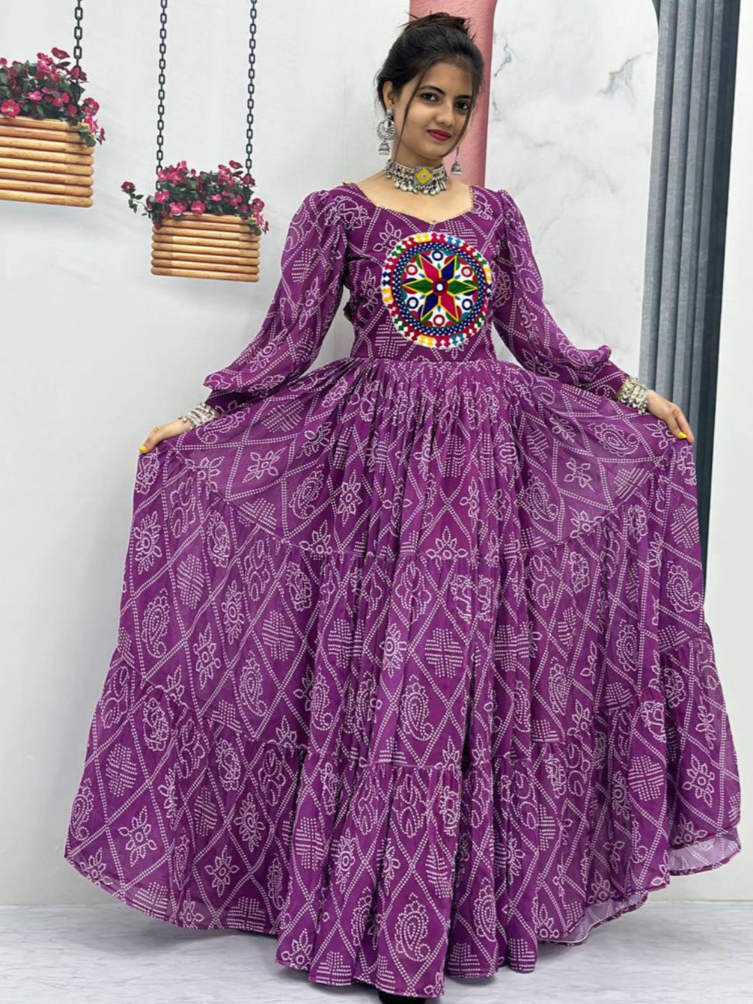 Woman wearing a purple traditional outfit with intricate patterns in a minimalistic setting.