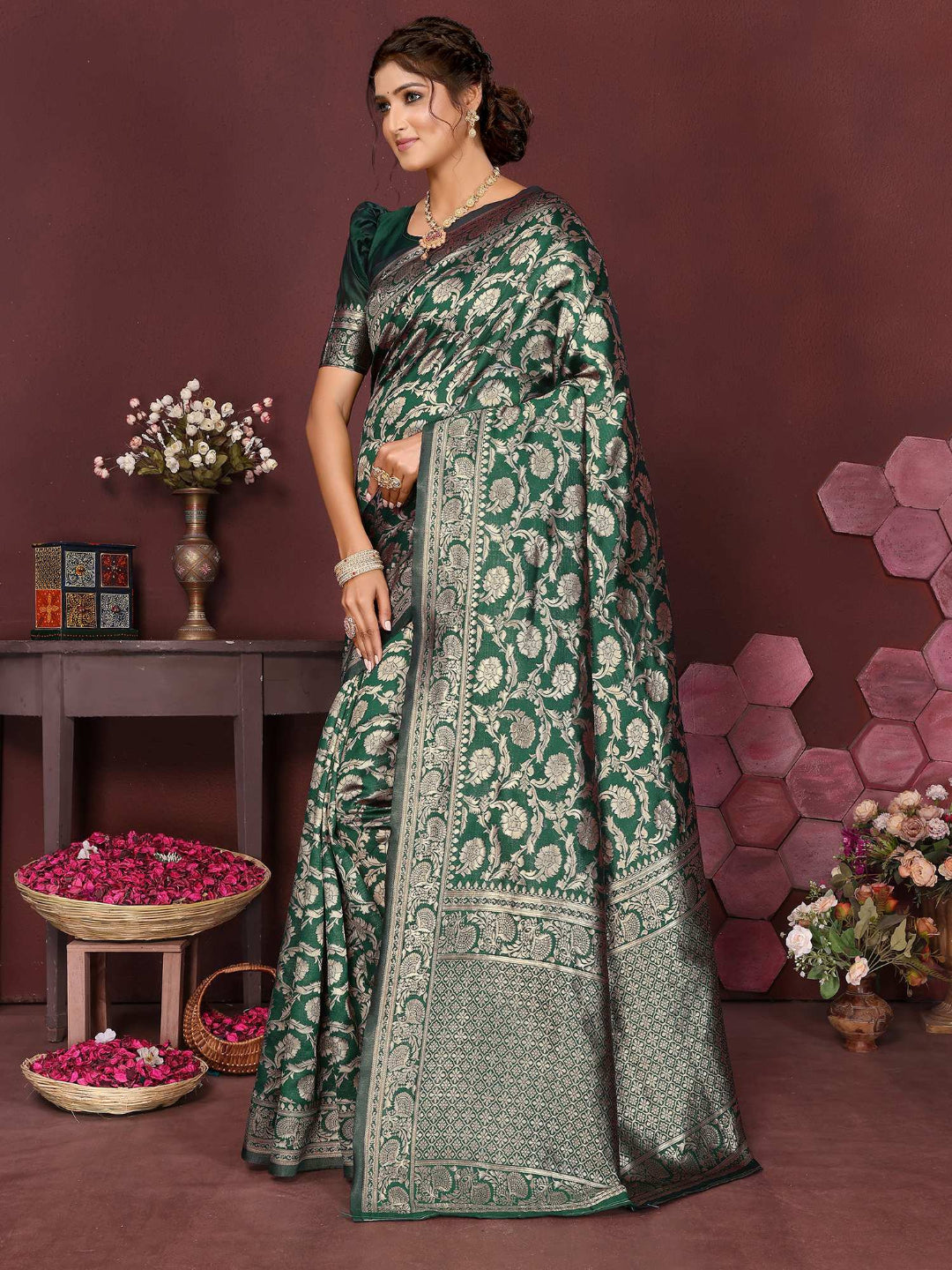 Woman wearing a green saree with a floral pattern in a decorated room.