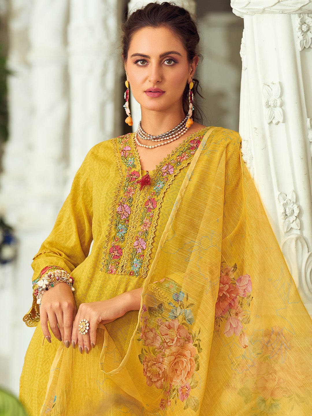 Woman wearing a yellow embroidered traditional outfit with floral patterns.