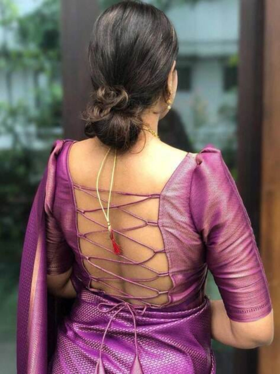 Purple saree with intricate back design worn by a person, blurred background