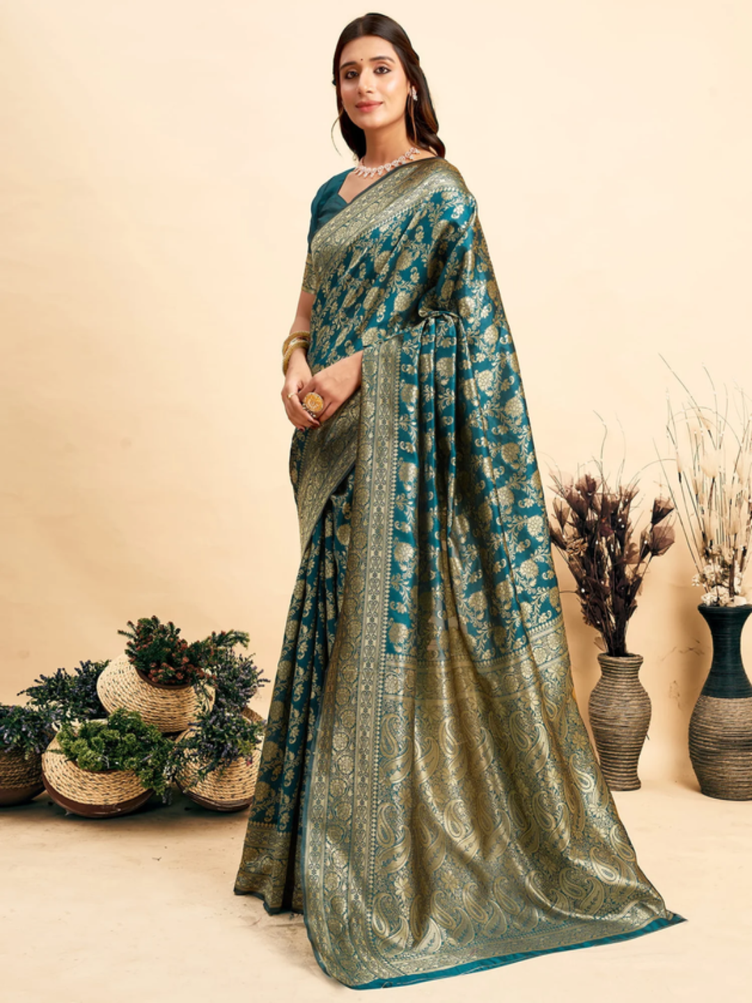 Woman wearing a green and blue saree with a neutral background