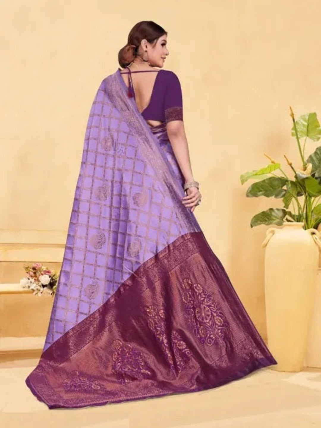 Woman wearing a purple saree with a checkered pattern on a beige background