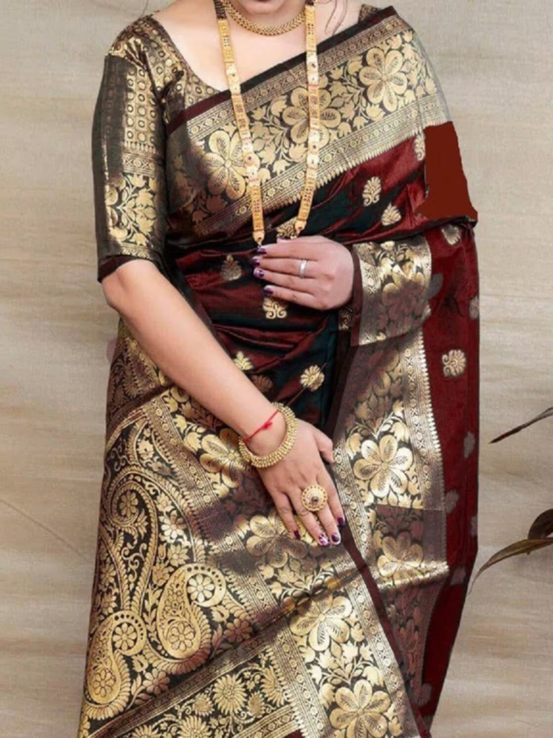 Woman wearing a traditional saree with gold and black patterns on a plain background