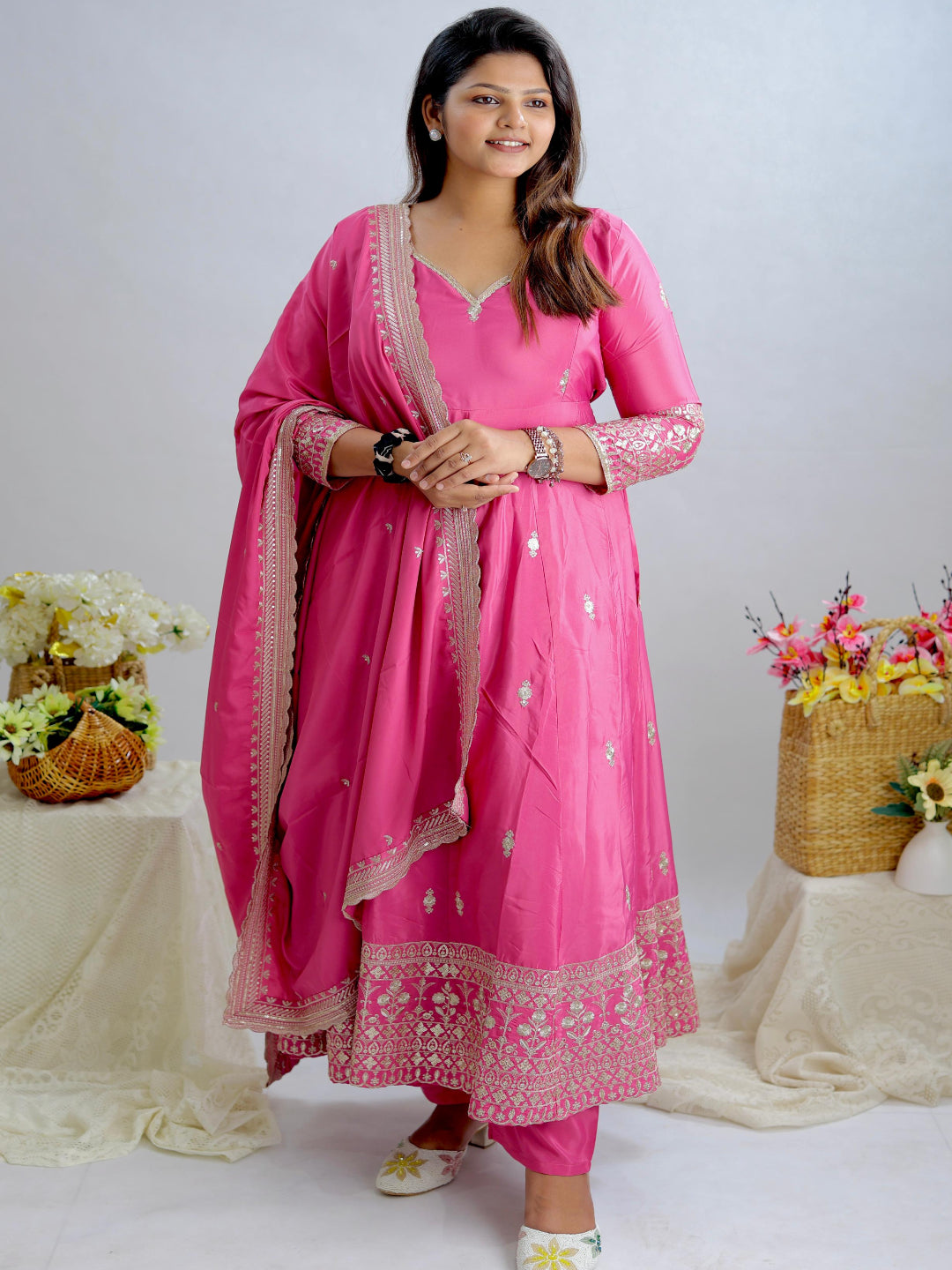 Woman in a pink traditional outfit with floral decorations on a white background