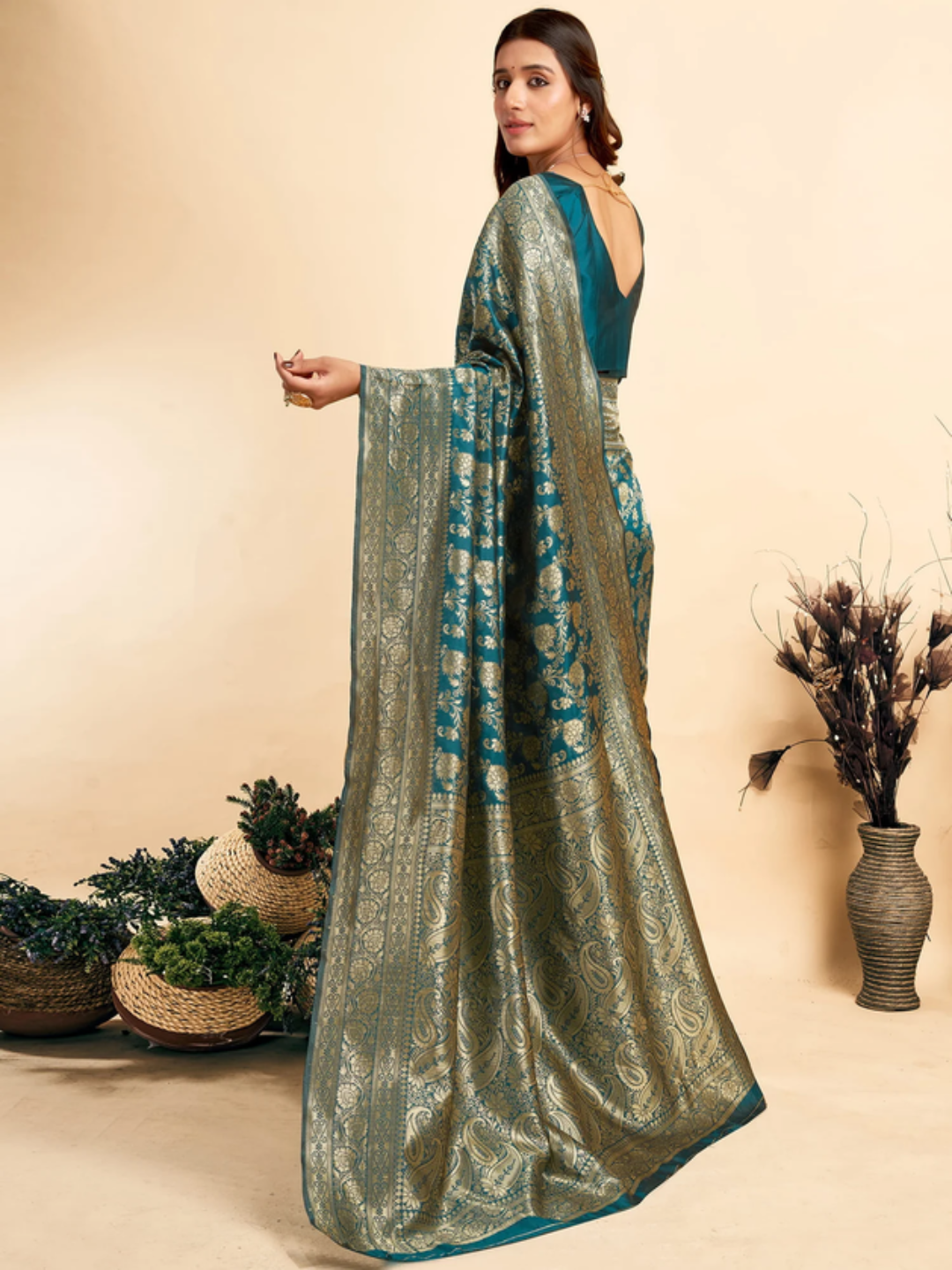 Woman in a green and blue saree with a beige background