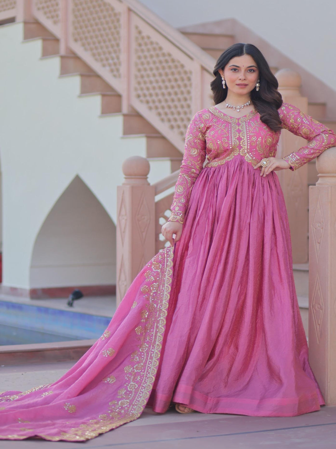 Woman in a pink traditional outfit standing on a staircase.