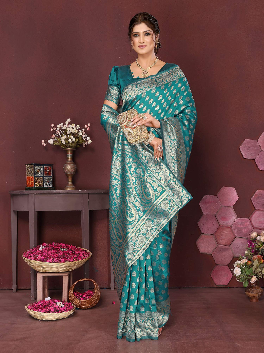 Woman in a teal saree with floral decorations and a brown background