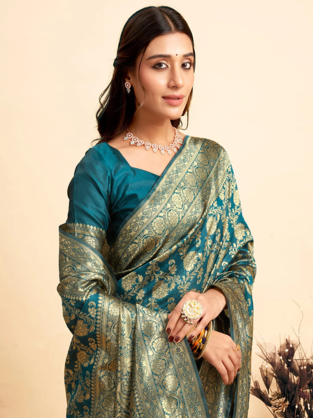 Woman wearing a traditional saree with intricate patterns on a beige background