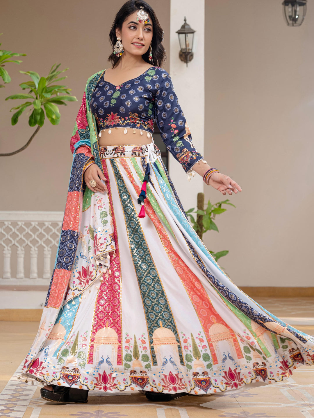 Woman in a colorful traditional outfit with a patterned skirt and top, standing indoors.