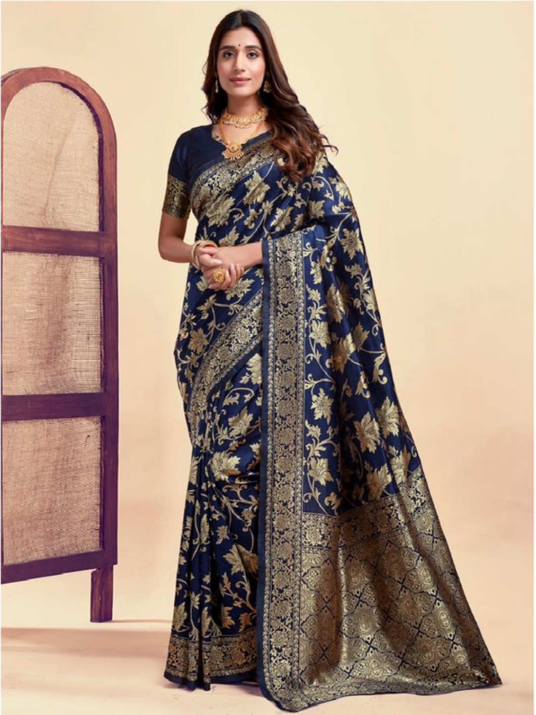 Woman wearing a blue and gold saree with a beige background