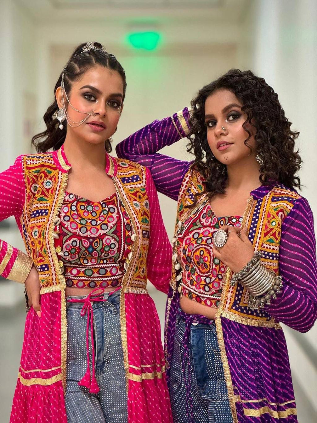 Two women in colorful traditional outfits posing together.