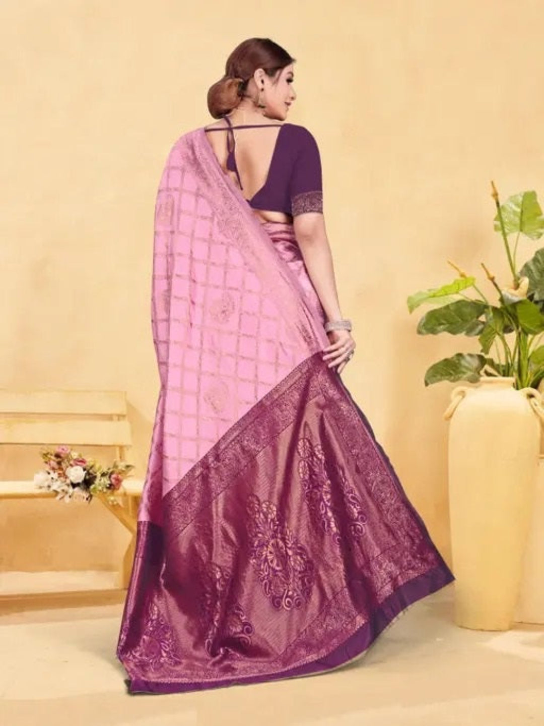 Woman wearing a pink and purple saree with a neutral background