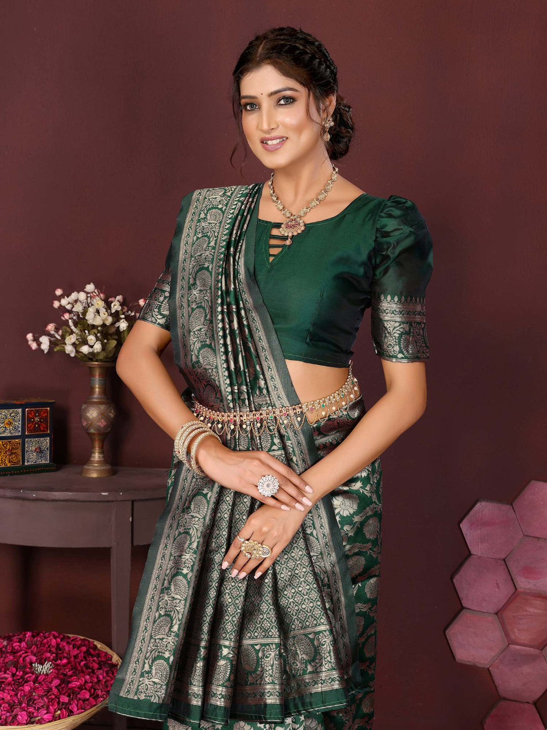 Woman in a green saree with a matching blouse against a maroon background