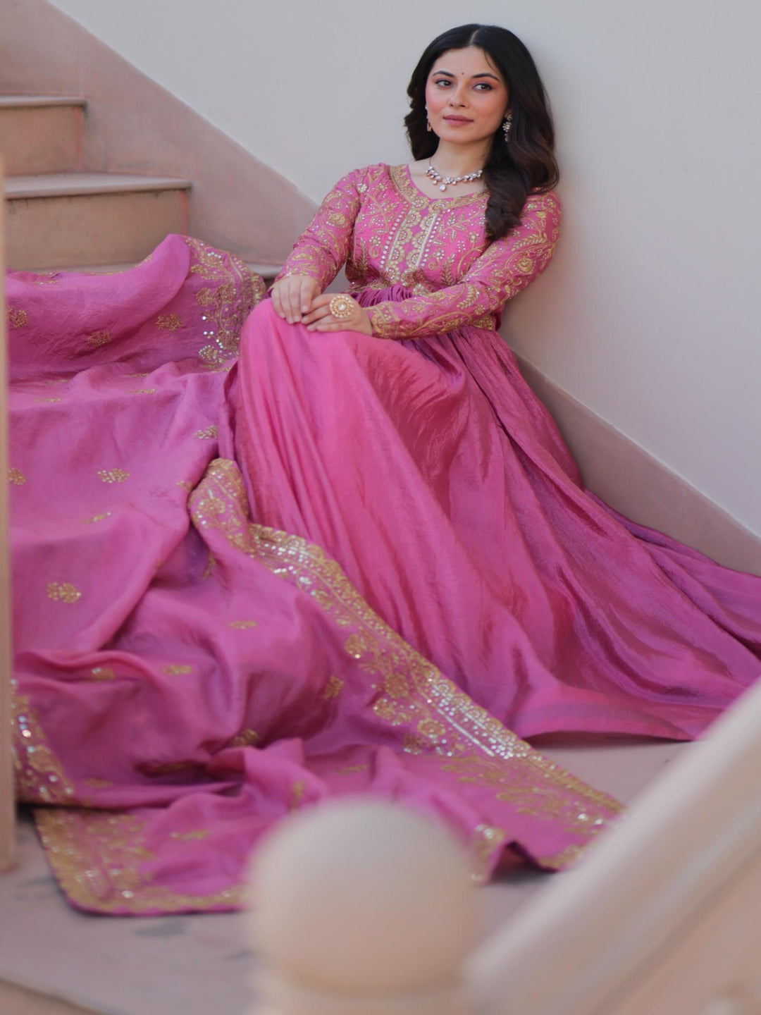 Woman in a pink traditional outfit sitting on a staircase.