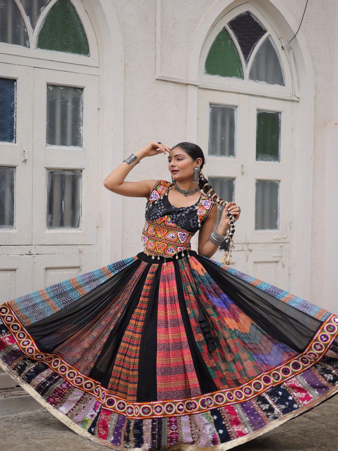 Woman in a colorful traditional outfit with a patterned skirt in an indoor setting.