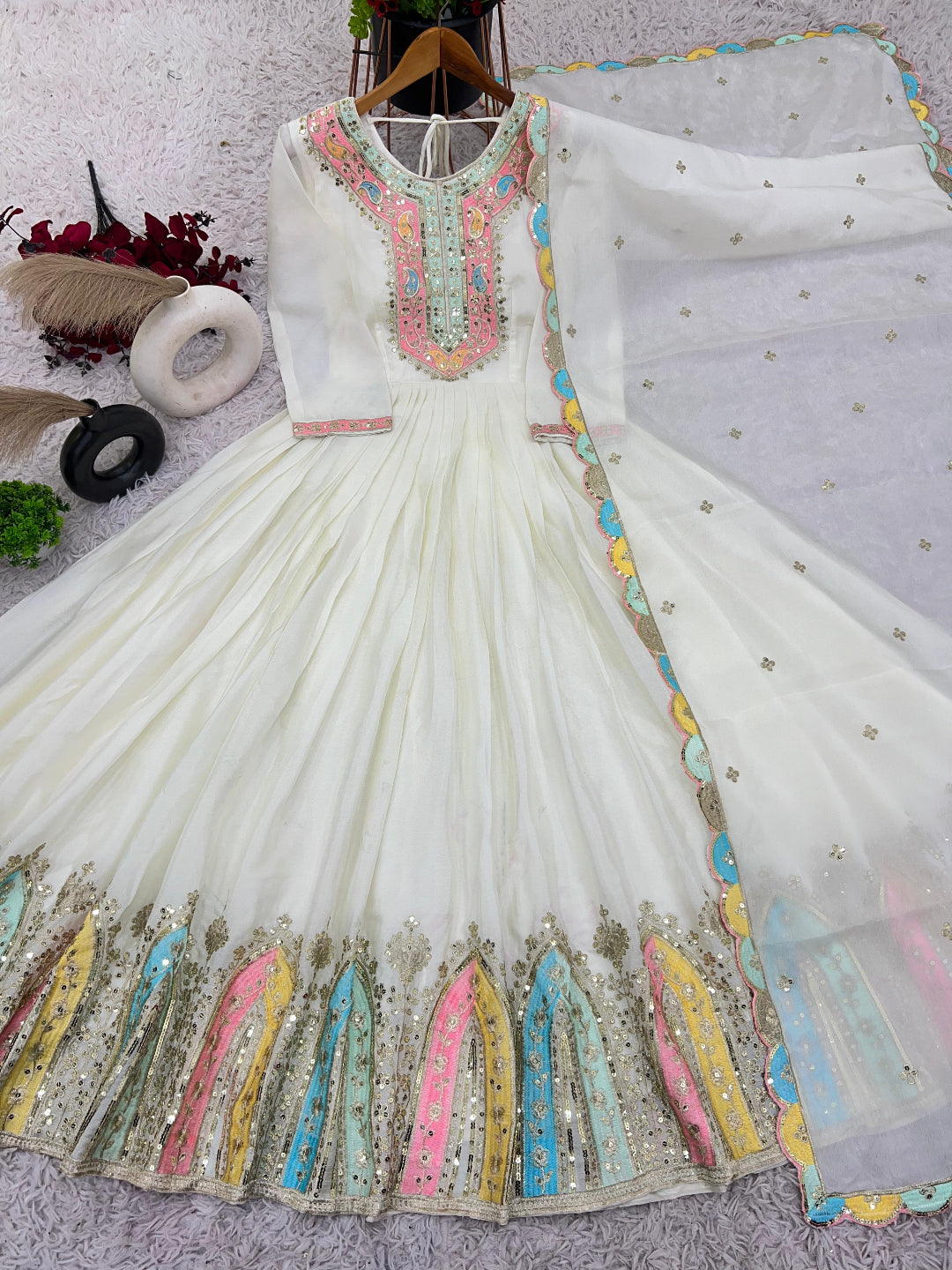 White embroidered dress with colorful details on a light gray background
