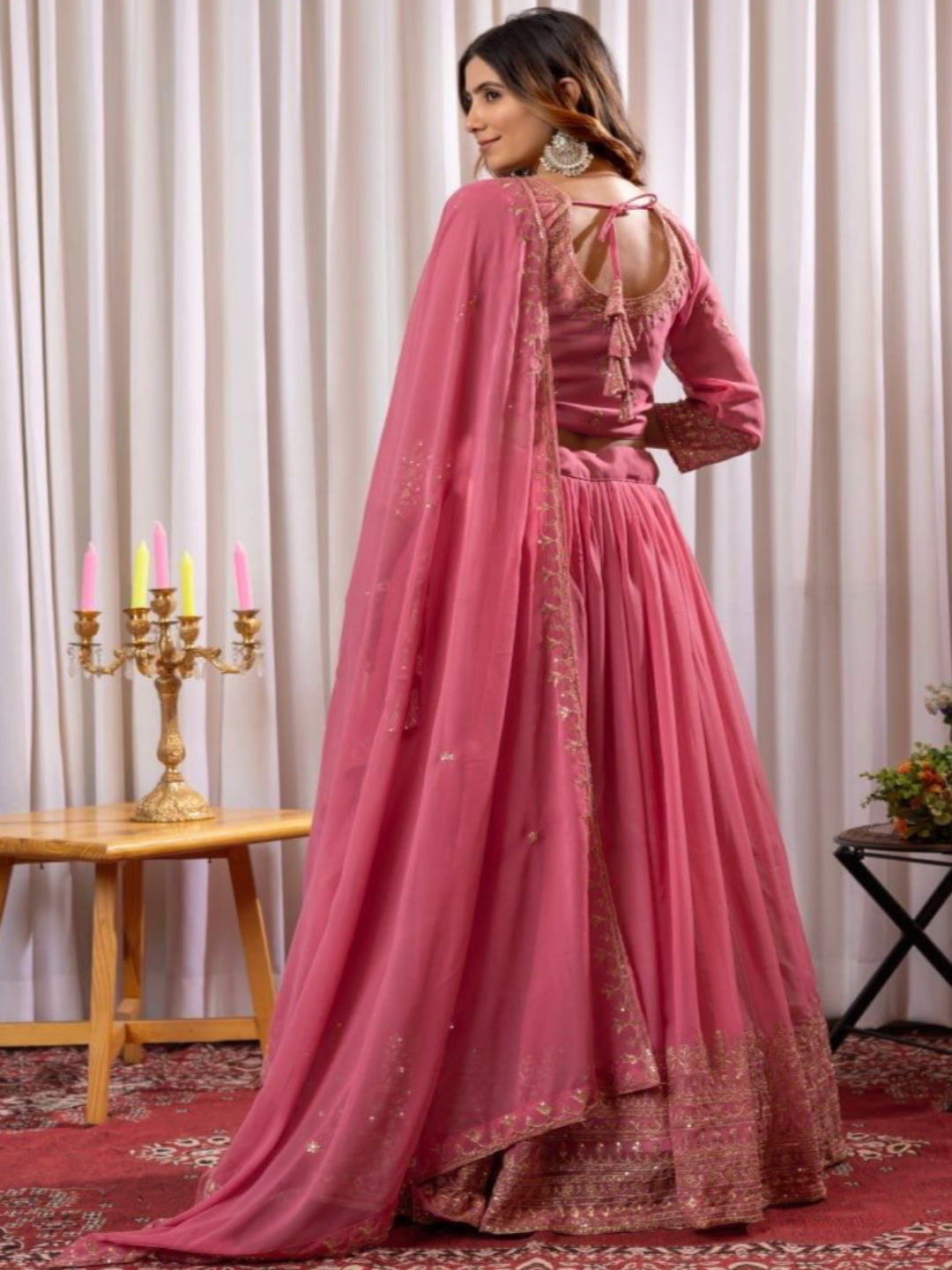 Woman in a pink traditional outfit standing against a plain background