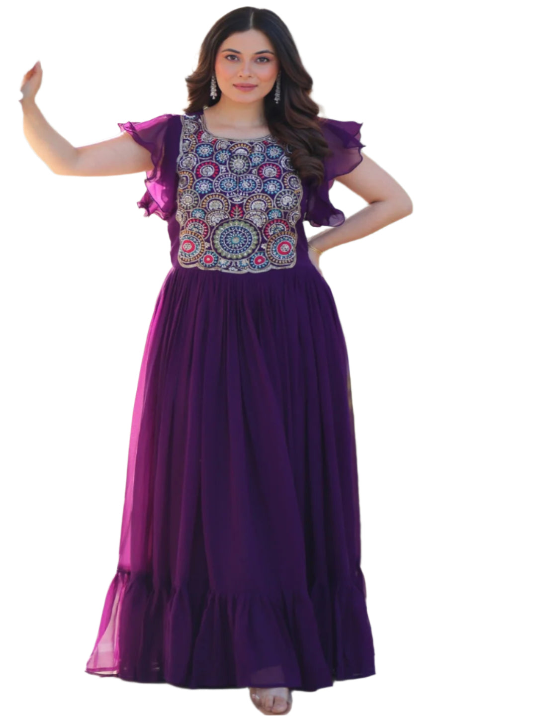 Woman in a floral top and purple skirt standing in front of decorative white pillars with greenery in the background.