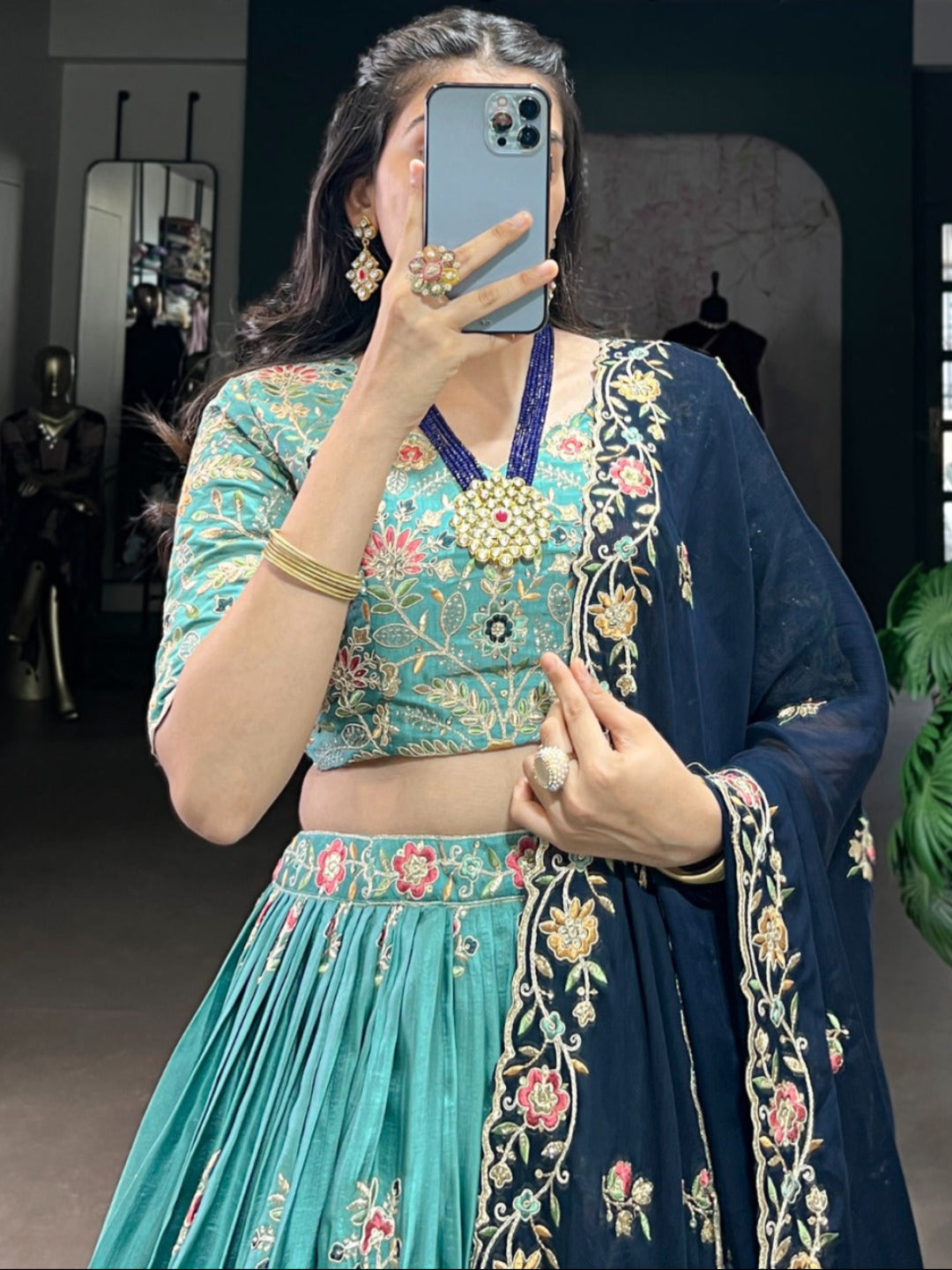 Person taking a mirror selfie wearing a traditional outfit with floral patterns.