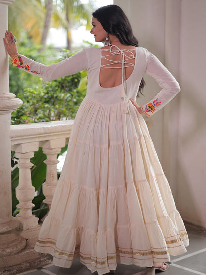 Woman in a white traditional outfit with floral sleeves standing on a balcony.