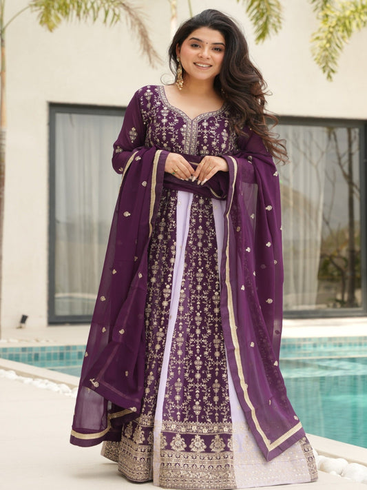 Woman in a purple traditional outfit standing by a pool with greenery in the background