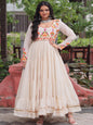 Woman in a traditional outfit with intricate patterns standing outdoors.