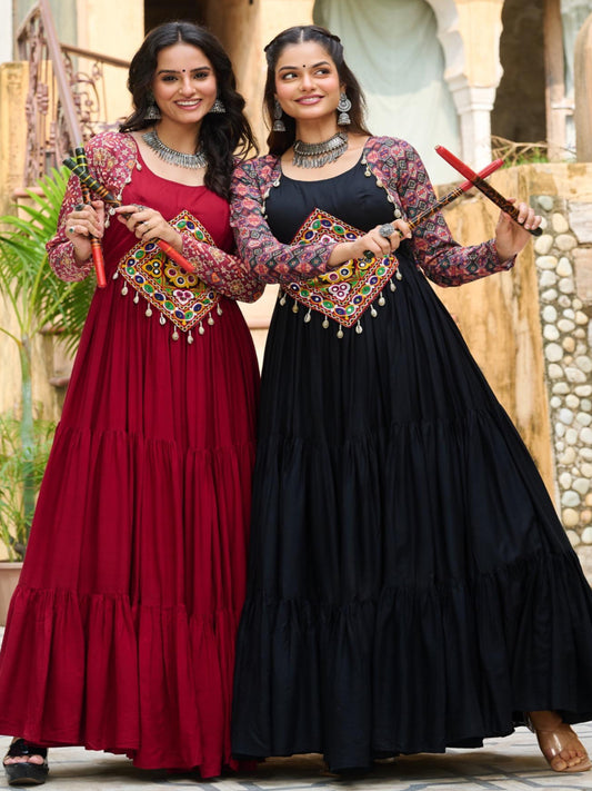 Two women in traditional dresses standing in front of a stone building.