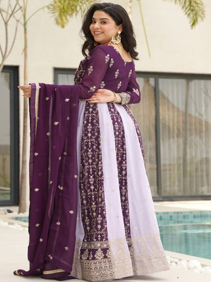 Woman in a purple traditional outfit standing by a pool with a building and trees in the background