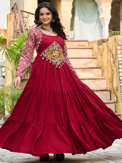 Woman in a red traditional dress with intricate patterns standing in front of a decorative archway.
